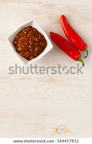 Red flaked chili pepper in white bowl and bean pods