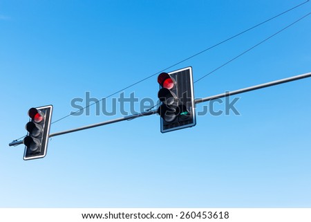 Traffic red lights with green right arrow against blue sky