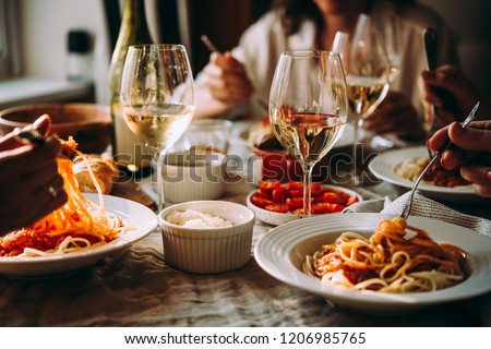 Friends having a pasta dinner at home of at a restaurant.