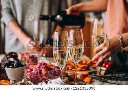 Pouring champagne at a dinner party with friends. Dinner table, celebrating Christmas or New Year eve.