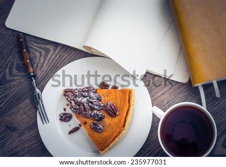 Tea, books and pumpkin cake on wooden background