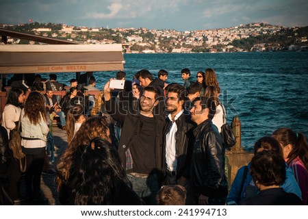 ISTANBUL, TURKEY - : october 23, 2014: Tourists are taking photo during a walk on a Bosphorus quay in front of the mosque on Ortakoy square, istanbul, Turkey.
