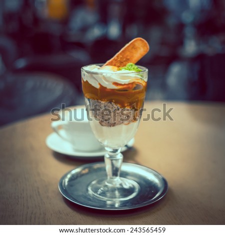 Ice cream dessert and cup of coffee  on the table in a cafe. Toned picture