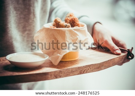 Deep fried pickles with garlic sauce on wooden board. Toned image