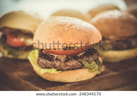 Party set of different burgers on wooden board. Toned image