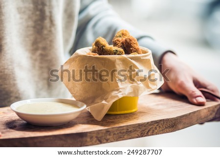 Deep fried pickles with garlic sauce on wooden board. Toned image