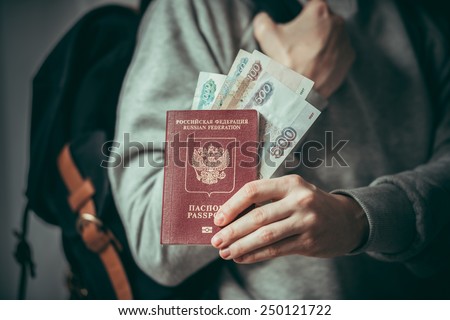 Tourist person holds russian passport and russian rouble bills. Toned picture