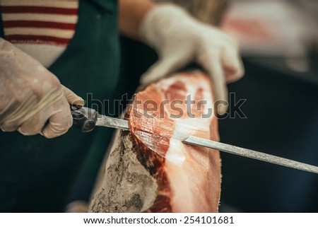 Slicing of italian dry-cured ham prosciutto. Toned image. Selective focus point