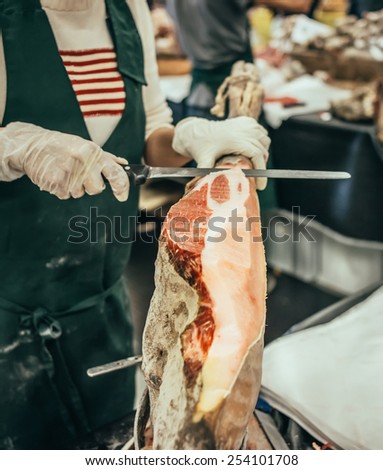 Slicing of italian dry-cured ham prosciutto. Toned image. Selective focus point
