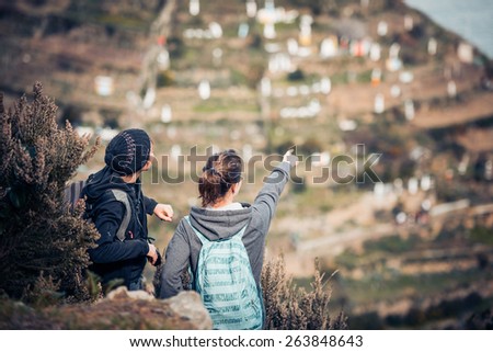 Two girl tourists with backpacks standing on  a mountain, searching the trail