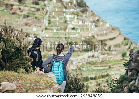 Two girl tourists with backpacks standing on  a mountain, searching the trail