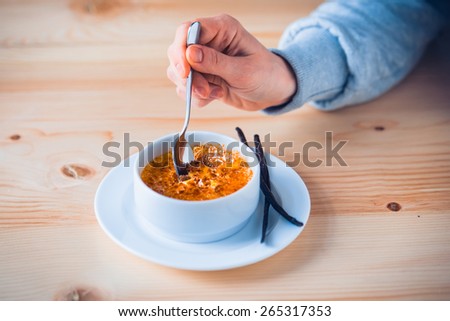 Creme brulee with bourbon vanilla sticks and hand with spoon