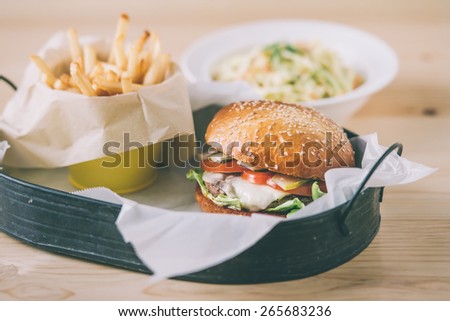 Lunch menu with classic american cheese burger, french fries and vegetable salad. Toned picture