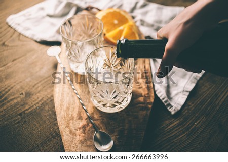 Pouring champagne or wine into a glass for making a cocktail. Toned image