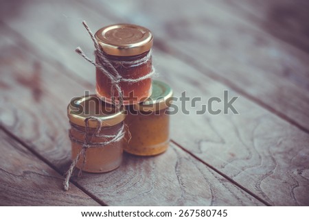 Three small jars of marmalade or jam on wooden table. Toned image