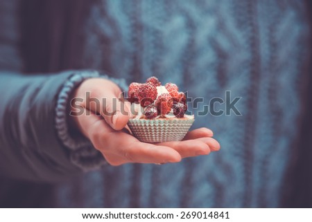 Small cake with strawberry in hand. Toned image