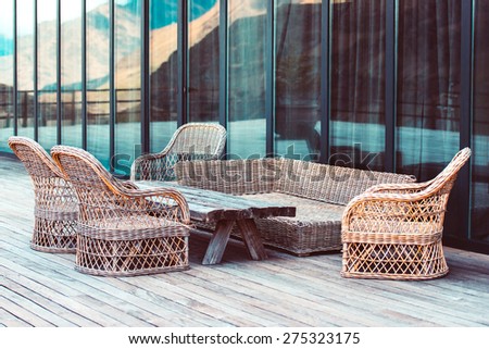 Rattan chairs and wooden table on terrace in mountains