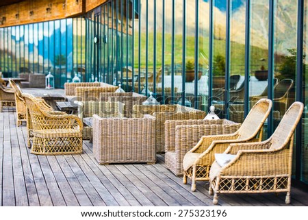 Rattan chairs and wooden table on terrace in mountains