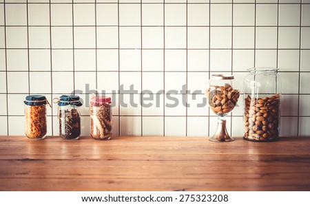 Jars with different grocery items on wooden kitchen table. Toned image