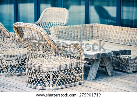 Rattan chairs and wooden table on terrace. Toned image