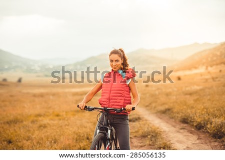 Beautiful girl riding on bicycle outdoor on the rural road. Wellness and sport concept