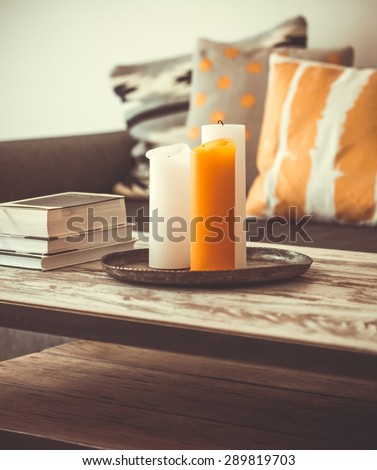 Modern wooden coffee table and cozy sofa with pillows. Living room interior and home decor concept. Toned image