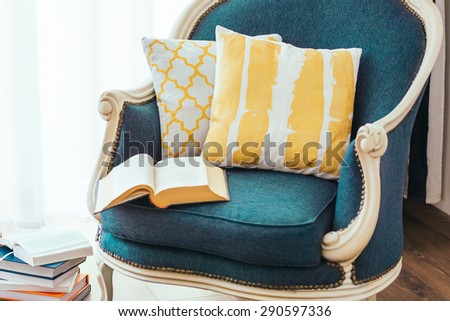 Cozy armchair with open book and decorative pillows. Interior and home decor concept
