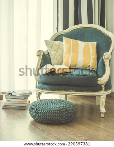 Cozy armchair with open book and decorative pillows. Interior and home decor concept. Toned image