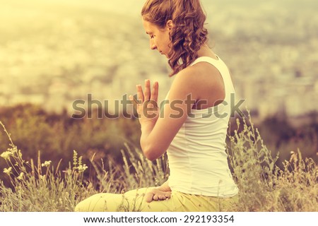Young woman sits in yoga pose with city on background Freedom concept Calmness and relax woman happiness Toned image Young woman sits in yoga pose with city on background Freedom concept Calmness and relax woman happiness Toned image