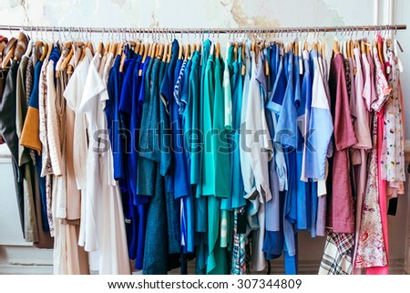 Colorful women\'s dresses on hangers in a retail shop. Fashion and shopping concept