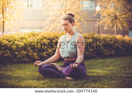 Yoga meditation in lotus pose in park.  Young woman in peace, soul and mind zen balance concept. Toned picture
