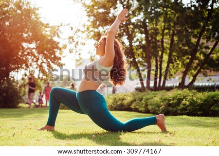 Young woman practicing yoga outdoor in park. Toned picture