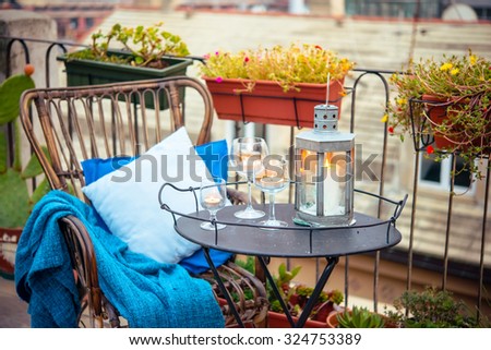 Beautiful terrace or balcony with cozy rattan armchair and candles on small iron table