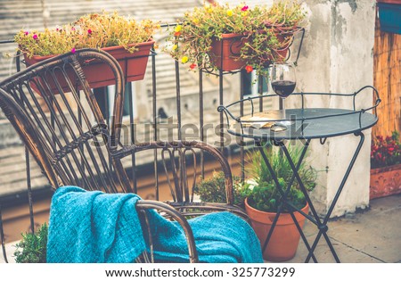 Beautiful terrace or balcony with small iron table, chair and wine glass. Toned image