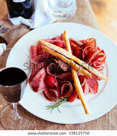Appetizers or tapas - sausage, meat and salami - on white plate with glass of wine