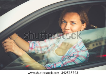 Young beautiful blonde woman drives a car. Toned image