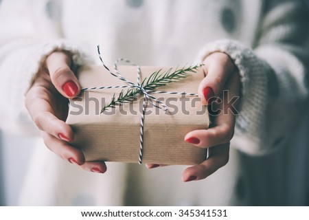 Woman\'s hands hold christmas or new year decorated gift box. Toned picture