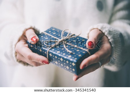 Woman\'s hands hold christmas or new year decorated gift box. Toned picture