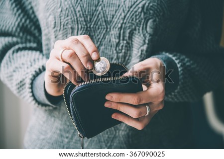 Hands holding british pound coin and small money pouch. Toned picture