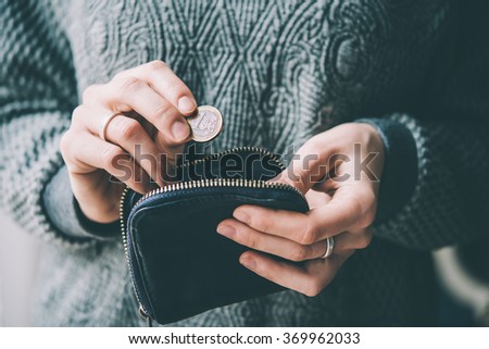 Hands holding one euro coin and small money pouch. Toned picture