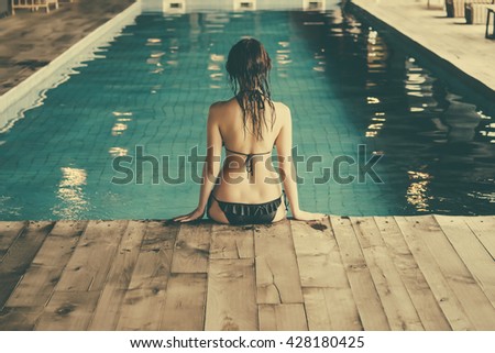 A young beautiful woman relaxes at the swimming pool. Wellness concept. Spa and relax, woman happiness. Toned picture
