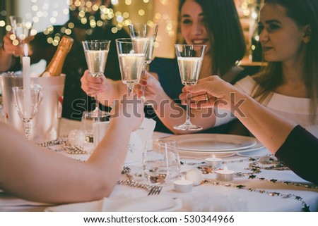 Friends celebrating Christmas or New Year eve. Party table with champagne. Toned picture