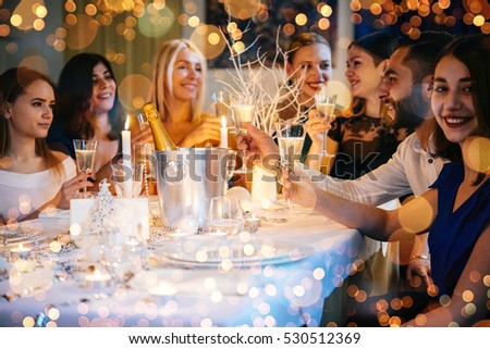 Friends celebrating Christmas or New Year eve. Party table with champagne.
