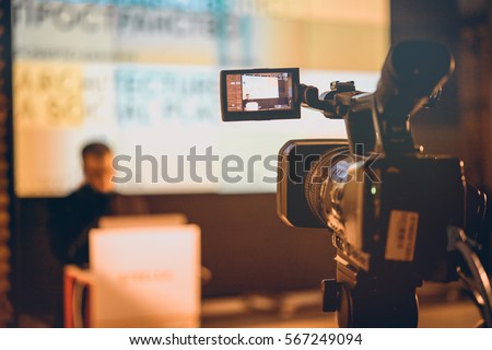 Filming creative video footage with professional video camera during the lection or meeting