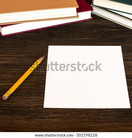 White card, pencil and books on the table./ White card, pencil and books on the table.