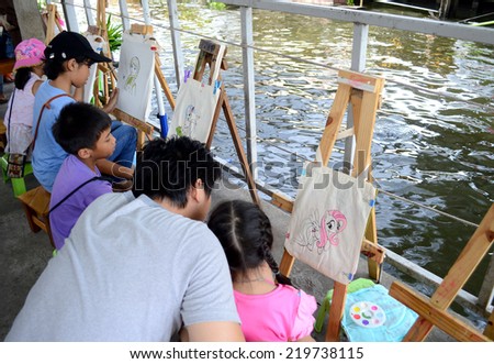 Bangkok - Sep 21, 2014 - unidentified kids paint their own cloth bag as hobby at  \'Klong Lad Mayom\' floating market in Bangkok, Thailand