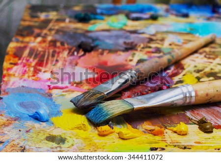 Used brushes on an artist's palette of colorful oil paint for drawing and painting