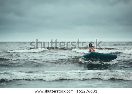 Girl travelling on air mattress in storm