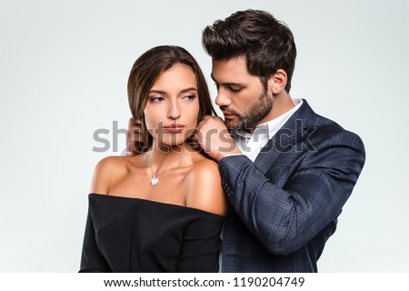 Perfect gift from loving man. Loving men putting necklace to his girlfriend while standing against white background