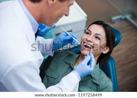 Amazing smile! Top view of dentist examining his beautiful patient in dentist’s office